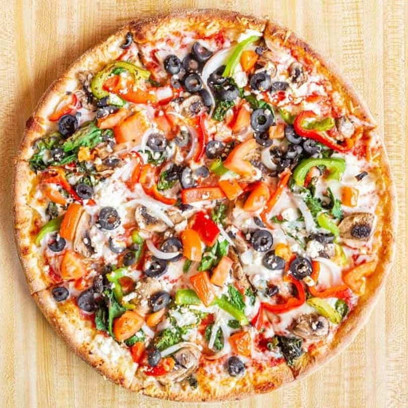 A whole Casa Pizza vegetarian pizza with olives, peppers, onions, mushrooms, and tomatoes.