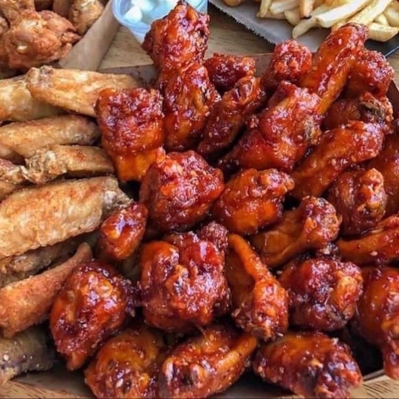 A close-up of a platter with two kinds of chicken wings, plain and sauced, and fries.